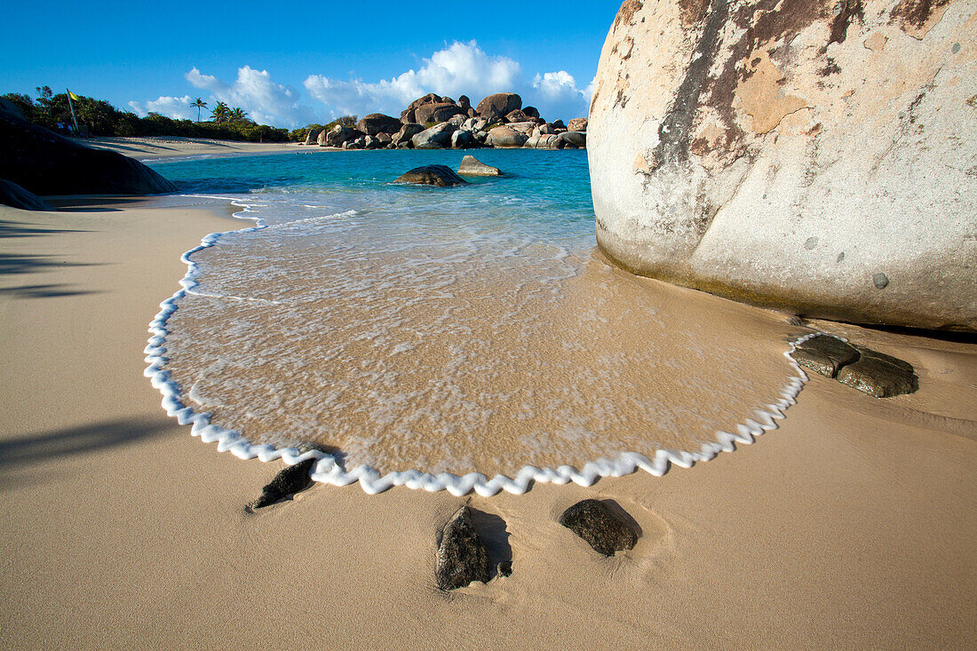 Atemberaubender Blick auf den Sandstrand mit der Brandung, die ein Zickzack-Muster in der Gischt neben den großen Felsbrocken bildet, die das Ufer von The Baths säumen, einem berühmten Strand auf den BVI's, Virgin Gorda, British Virgin Islands, Karibik