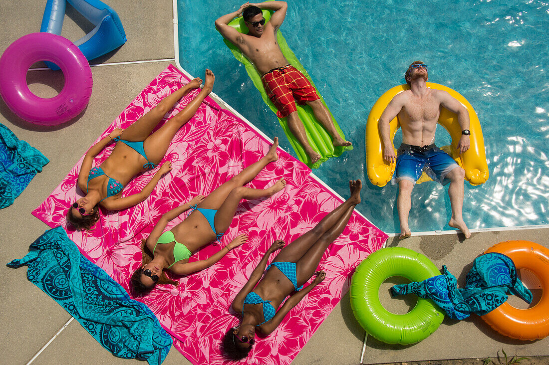 Blick von oben auf eine Gruppe junger erwachsener Freunde, die sich an einem heißen Tag am Pool vergnügen, Virginia Beach, Virginia, Vereinigte Staaten von Amerika