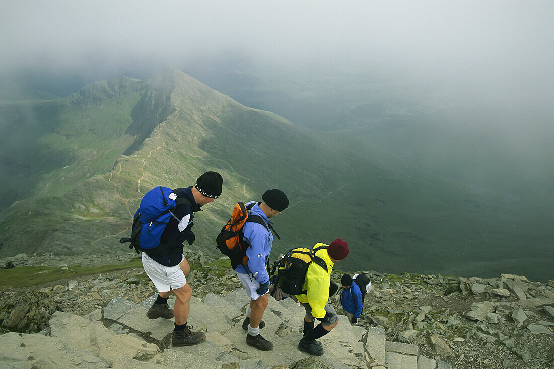 Wanderer steigen über Steinstufen hoch oben am Mount Snowdon in Wales ab,Wales