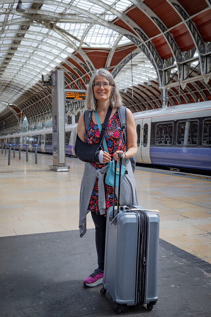 Mature woman waits with luggage at a train station,United Kingdom