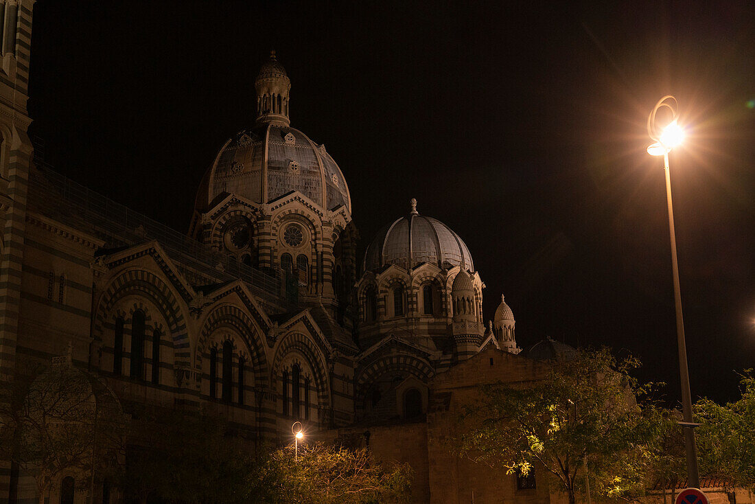 Kuppeln der historischen Kathedrale von Marseille bei Nacht, mit einer Straßenlaterne, die in der Dunkelheit hell leuchtet, Marseille, Frankreich
