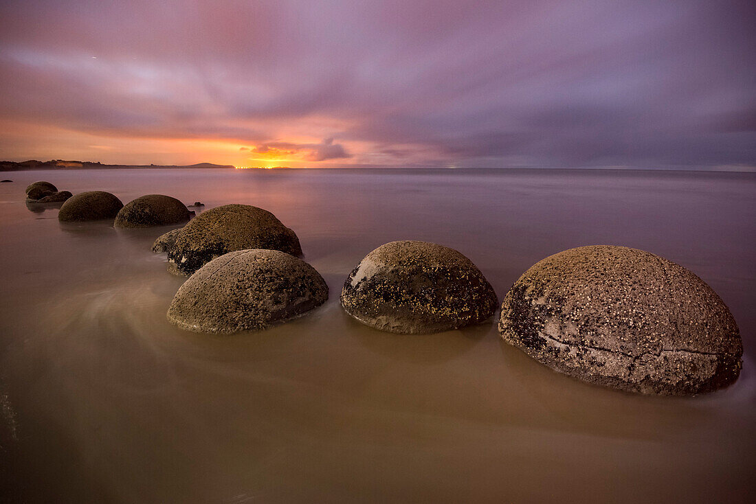 Beleuchtete Moeraki Boulders entlang des Koekohe Beach auf der Südinsel Neuseelands in der Dämmerung, Hampden, North Otago, Neuseeland