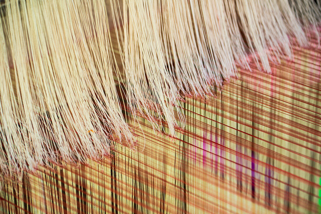 Stränge aus feinem Garn bei der Herstellung von Stoffen auf einem Webstuhl in Ock Pop Tock, dem lebenden Handwerkszentrum, Luang Prabang, Laos