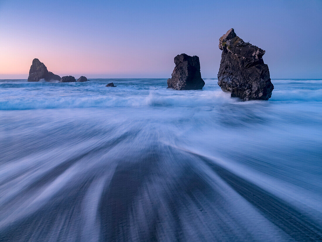 Waves wash over a beach at sunset,Haast,South Island,New Zealand