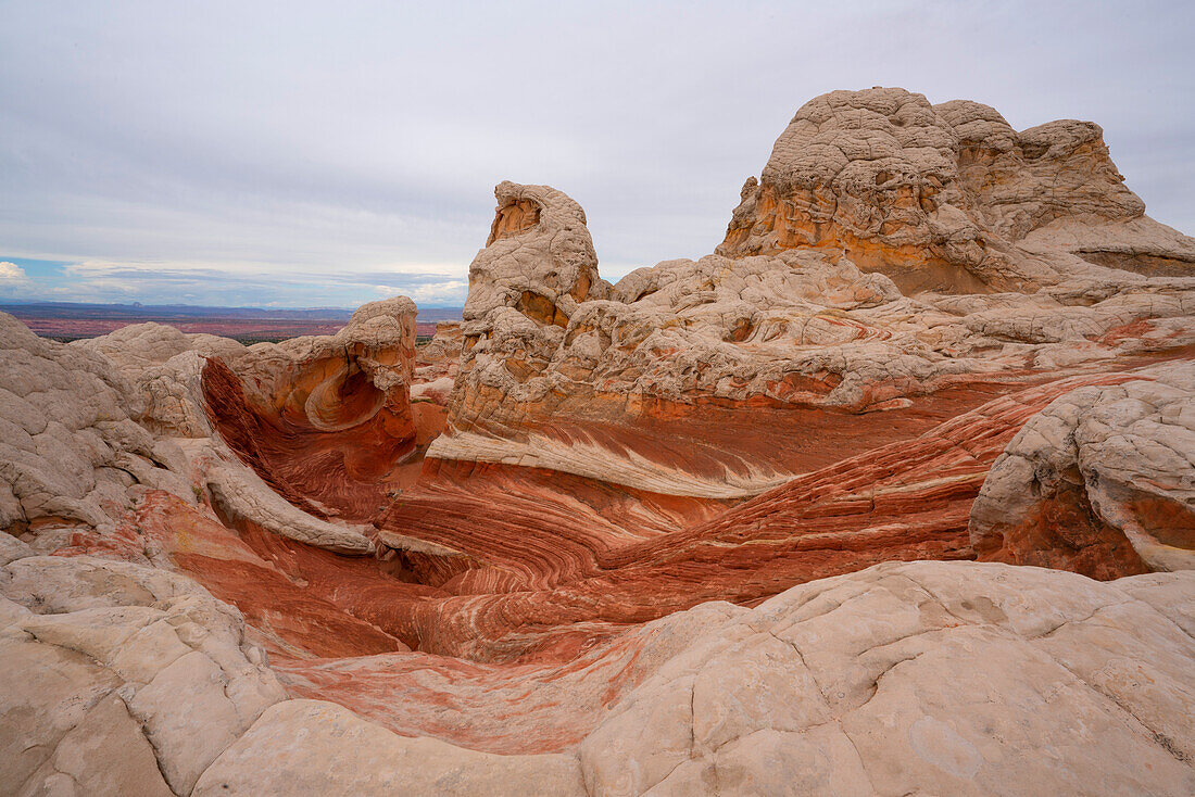Landschaftliche Ansicht von wirbelnden Mustern und hügeligen Felsformationen unter einem bewölkten Himmel, die Teil der fremden Landschaft mit erstaunlichen Linien, Konturen und Formen in dem wundersamen Gebiet, das als White Pocket bekannt ist, in Arizona, Arizona, Vereinigte Staaten von Amerika