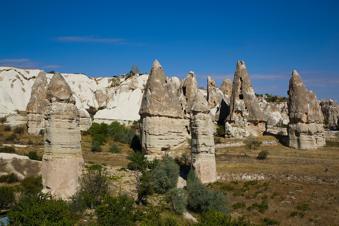 Cave Houses carved into the volcanic rock formations,Fairy Chimneys,against a bright blue sky near the Town of Goreme in Pigeon Valley,Cappadocia Region,Nevsehir Province,Turkey