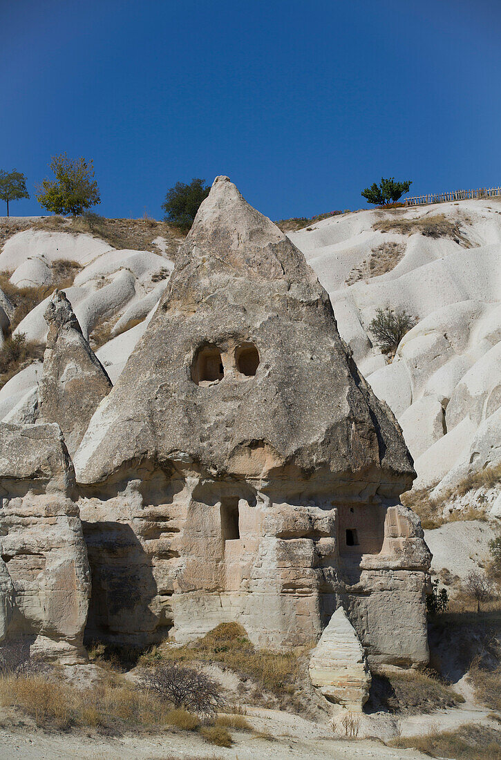 Nahaufnahme eines in die vulkanischen Felsformationen gehauenen Felsenhauses, eines Fairy Chimney, vor einem strahlend blauen Himmel in der Nähe der Stadt Goreme im Pigeon Valley, Region Kappadokien, Provinz Nevsehir, Türkei