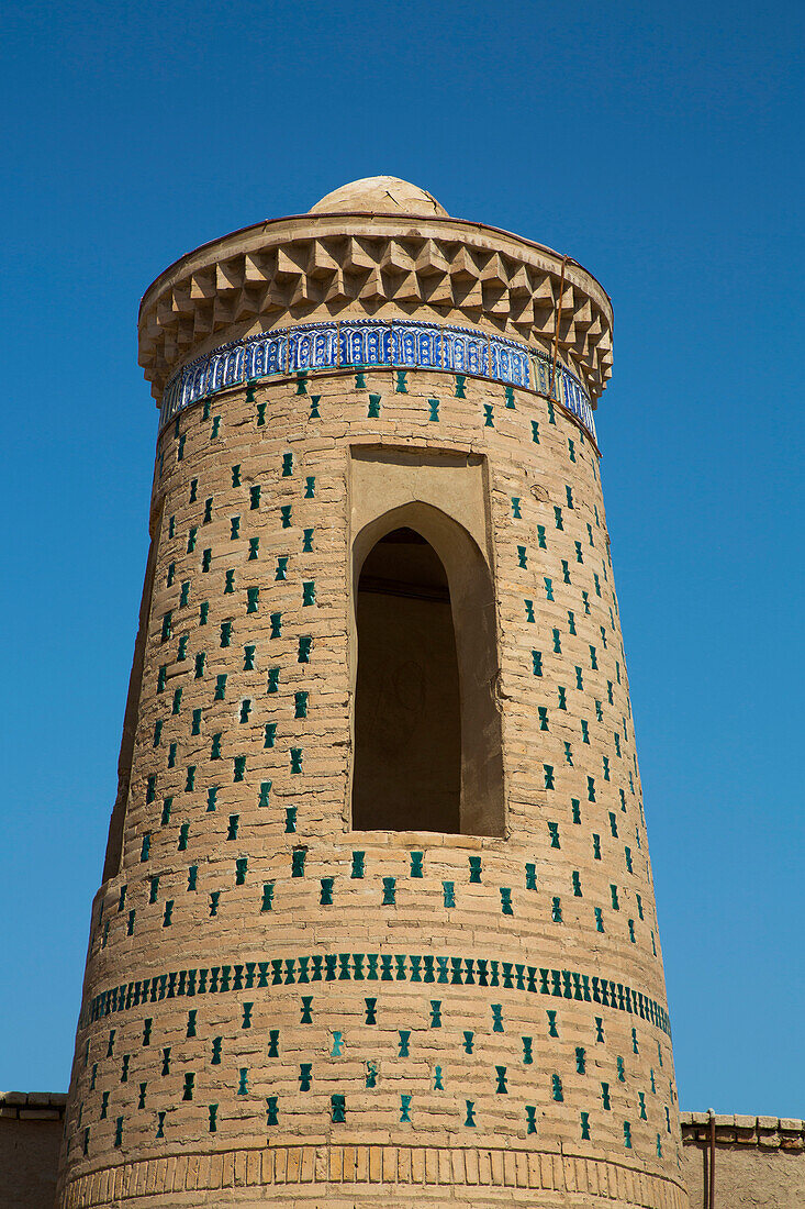 Turm mit dekorativem Muster vor strahlend blauem Himmel in Itchan Kala, Chiwa, Usbekistan