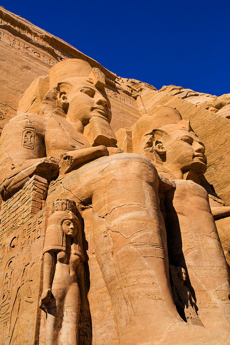 Nahaufnahme von zwei in den Berghang gehauenen Statuen von Ramses II. an der Vorderseite des Großen Sonnentempels von Abu Simbel, Abu Simbel, Nubien, Ägypten