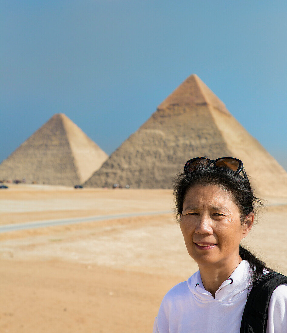 Nahaufnahme einer asiatischen Touristin, die vor den Großen Pyramiden von Gizeh steht,Gizeh,Kairo,Ägypten