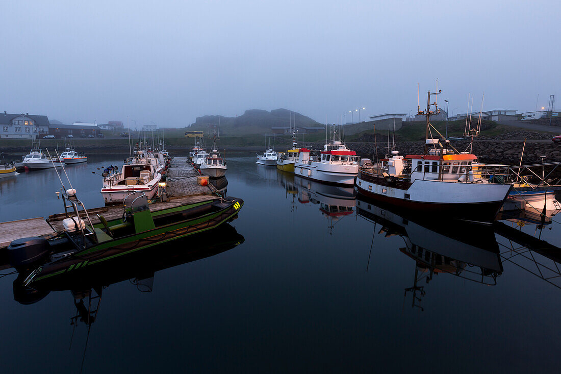 The fishing boats in the harbour docks of Djupivogur,Eastern iceland sitting in light fog in the middle of the night during summer solstice,Djupivogur,Iceland