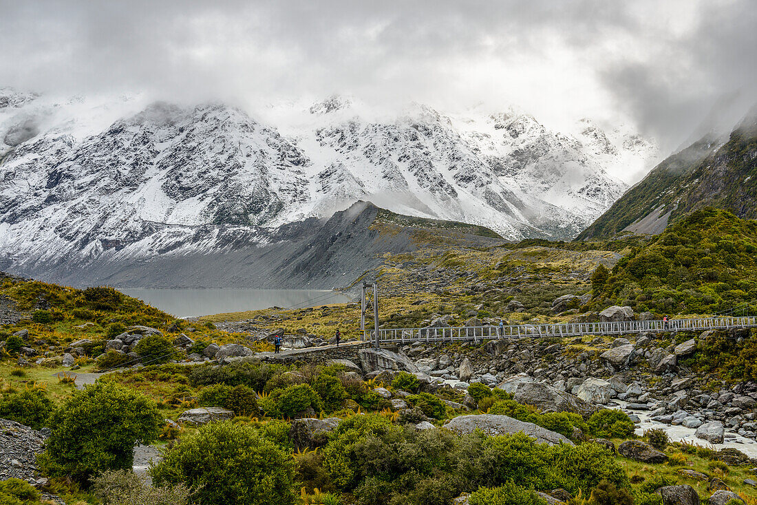 Schneebedeckte Berge und Hängebrücke entlang des Hooker Valley Track, Mount Cook National Park, Südinsel, Neuseeland