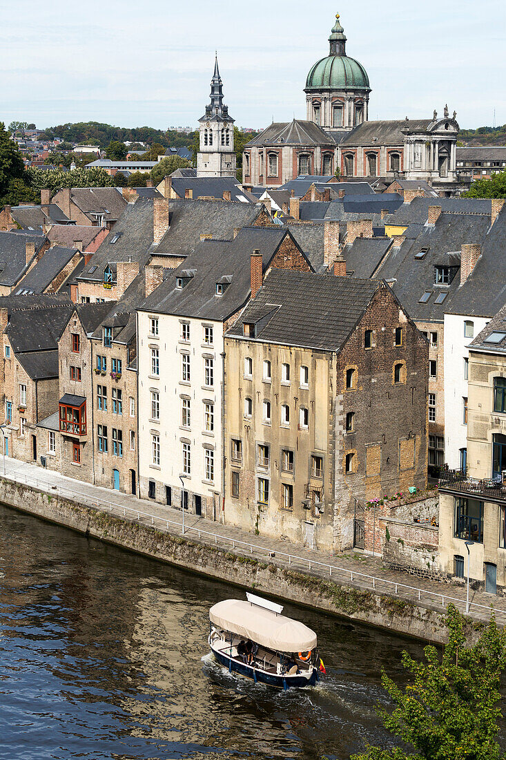 Ausflugsboot auf einem Kanal mit mittelalterlichen Steinbauten am Ufer und einer großen Kathedrale im Hintergrund,Namur,Belgien