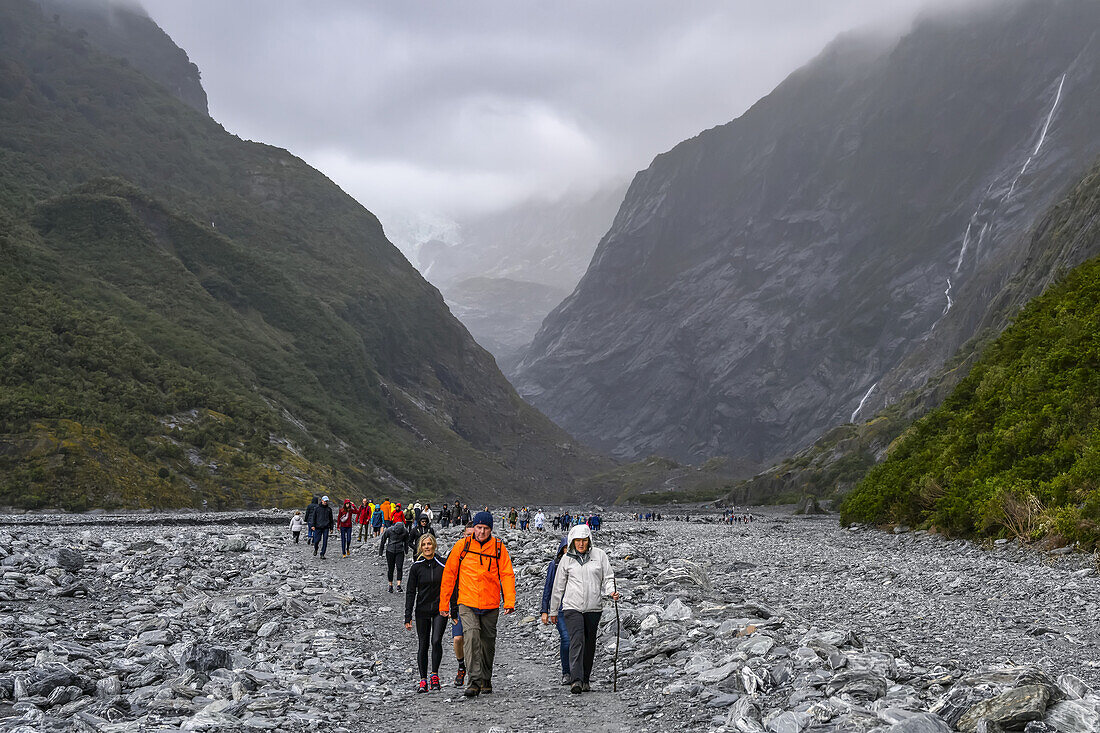 Tour group hiking on a rocky footpath along the Franz Josef Glacier Walk in the Westland Tai Poutini National Park on a foggy day,Whataroa,West Coast Region,South Island,New Zealand