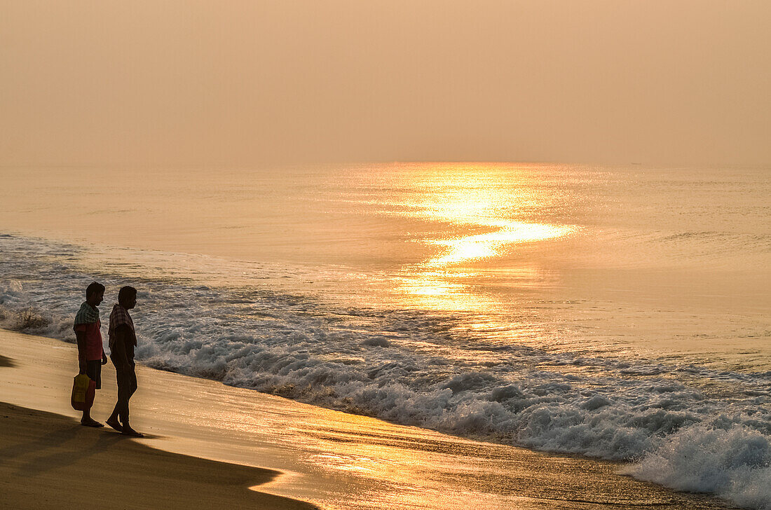 Young men on the shore and looking at the sea at sunset,Puri Beach,Puri,Odisha State,India