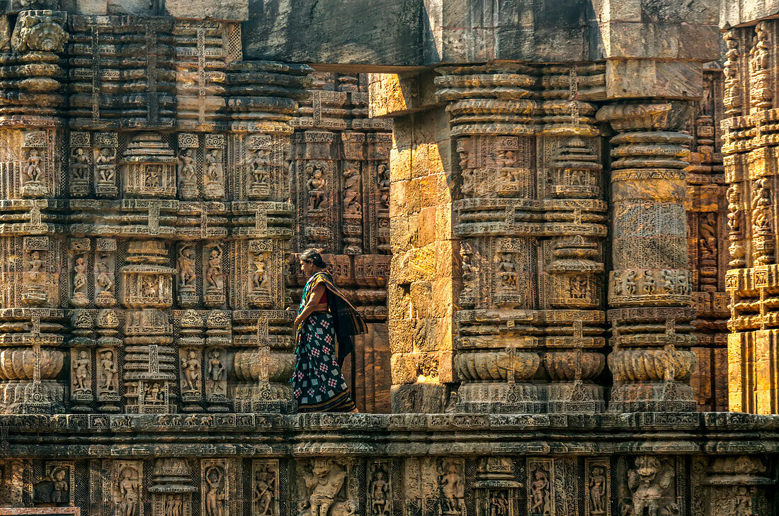 Frau im Sari geht an den Innenwänden des Sonnentempels von Konark entlang, Odisha, Indien