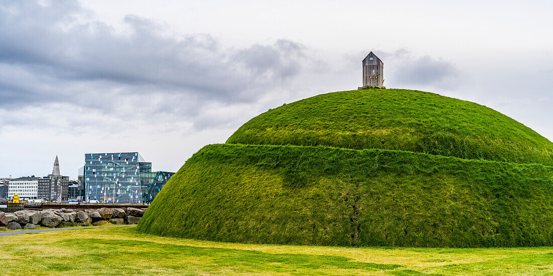Ein Hügel mit grünem Gras und Blick auf die Harpa-Konzerthalle und das Konferenzzentrum im Hintergrund, Reykjavik, Reykjavik, Island