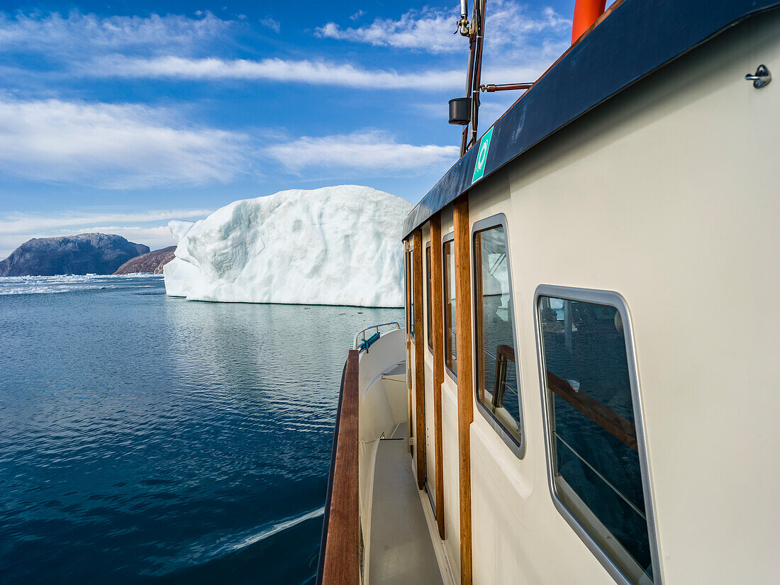 Blick auf die Seite eines Ausflugsbootes, das entlang der zerklüfteten Küste Grönlands in Richtung eines Eisbergs fährt,Nuuk,Sermersooq,Grönland