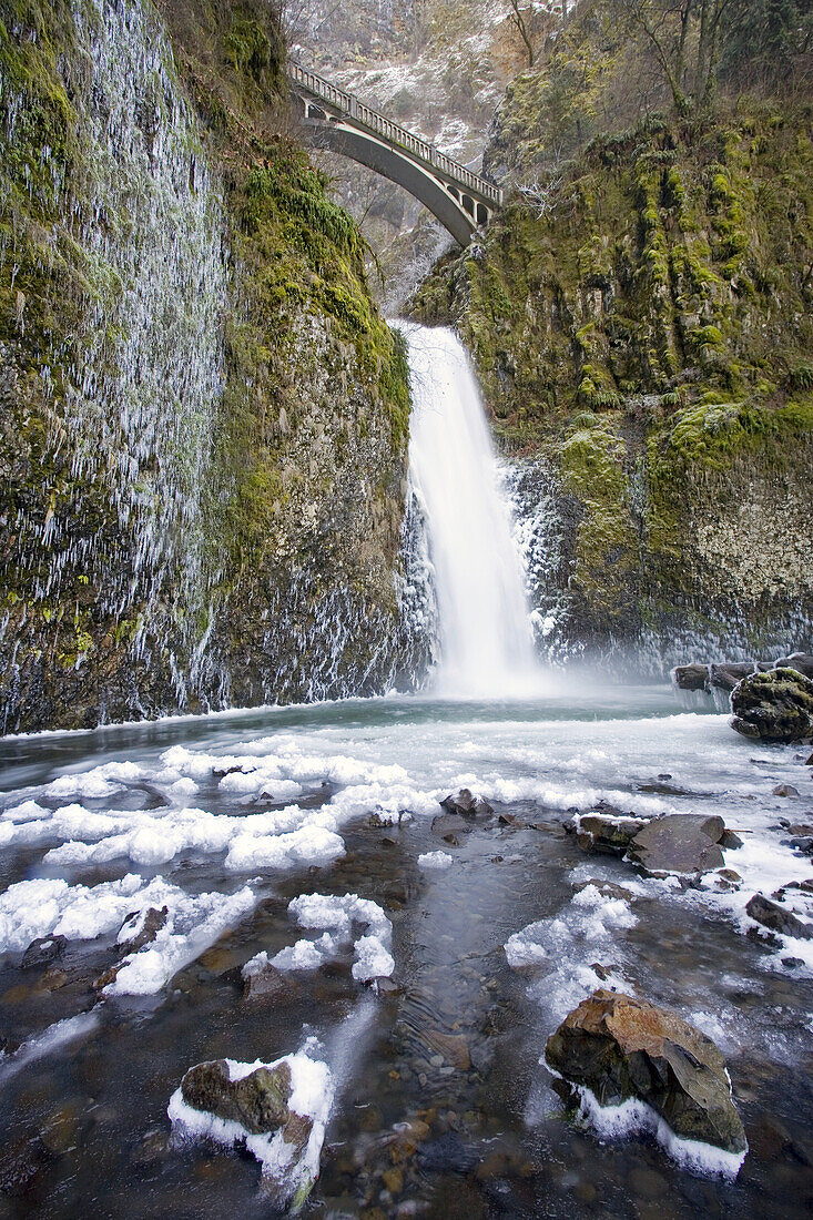 Wasserfall von einer Klippe im Winter, Multnomah Falls mit einer Aussichtsbrücke darüber, Columbia River Gorge, Oregon, Vereinigte Staaten von Amerika