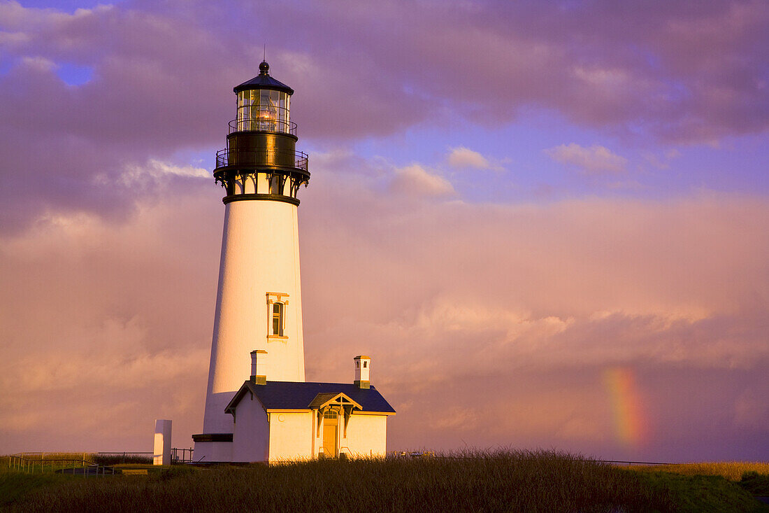 Yaquina Head Light bei Sonnenaufgang mit einem Regenbogen in den Wolken, Oregon, Vereinigte Staaten von Amerika