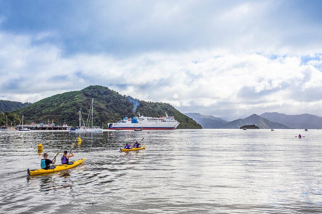 Kajaks treiben im Hafen, während die Inter-island Ferry in den Hafen von Picton auf der Südinsel Neuseelands einläuft, Picton, Marlborough, Neuseeland