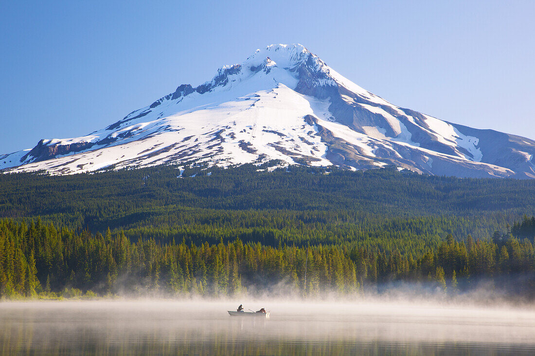 Majestic Mount Hood and Trillium Lake,with mist rising off the water and people boating and fishing in the tranquil water,Oregon,United States of America