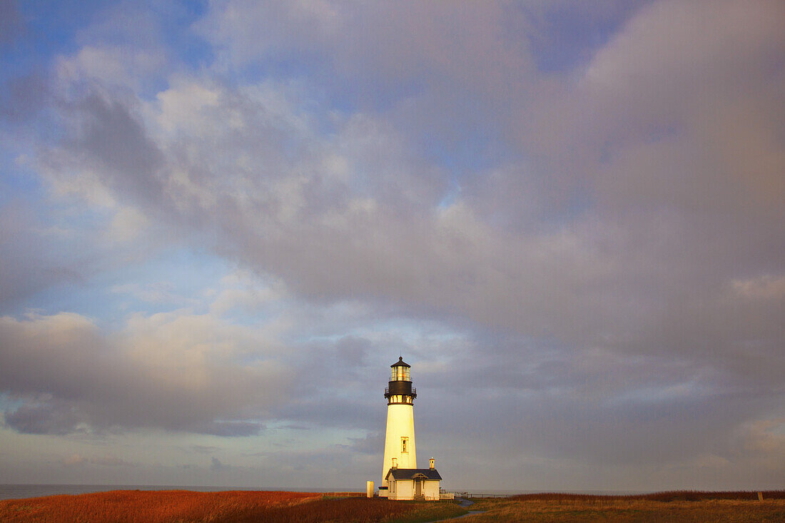 Yaquina Head Light under a cloudy sky along the Oregon coast with the horizon of the pacific ocean in the background,Oregon,United States of America