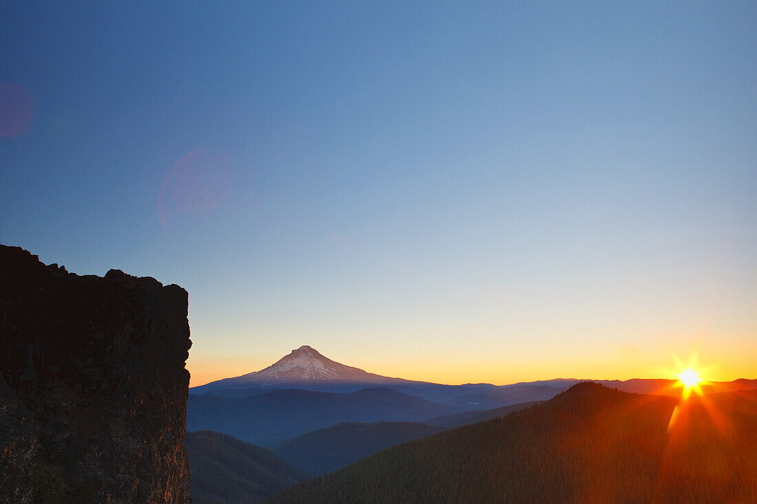 Mount Hood with a sunburst over the horizon at sunrise,Oregon,United States of America