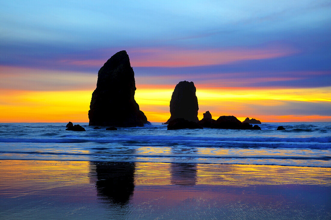 Silhouetted sea stacks along the Oregon coast at sunset with the sky displaying multiple glowing colours,Ecola State Park,Cannon Beach,Oregon,United States of America