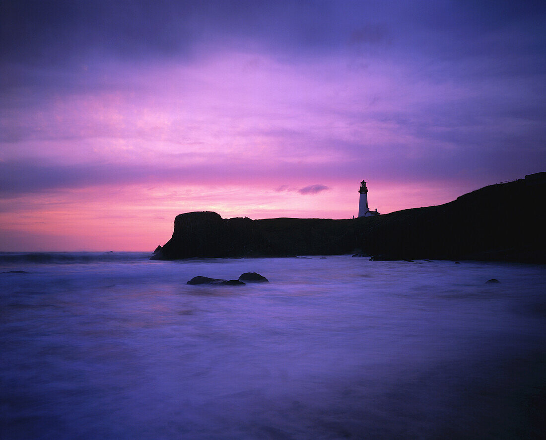 Yaquina Head Light vor einem glühend rosafarbenen Himmel bei Sonnenuntergang, Oregon, Vereinigte Staaten von Amerika