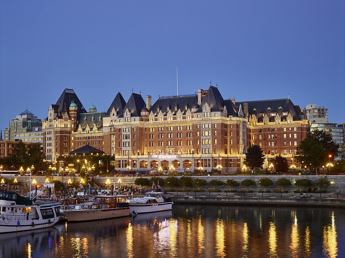 Das Fairmont Empress Hotel und Boote im Innenhafen von Victoria in der Abenddämmerung, Victoria, British Columbia, Kanada