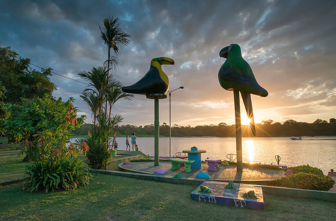 A family looks out over the waterway as the sun sets over the village of Tortuguero,Costa Rica,Tortuguero,Limon Province,Costa Rica