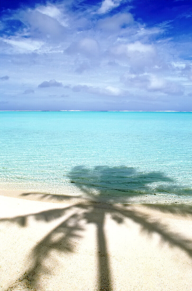 Schatten einer Palme auf weißem Sand und türkisfarbenem Meerwasser auf einer Insel in Bora Bora, Französisch-Polynesien