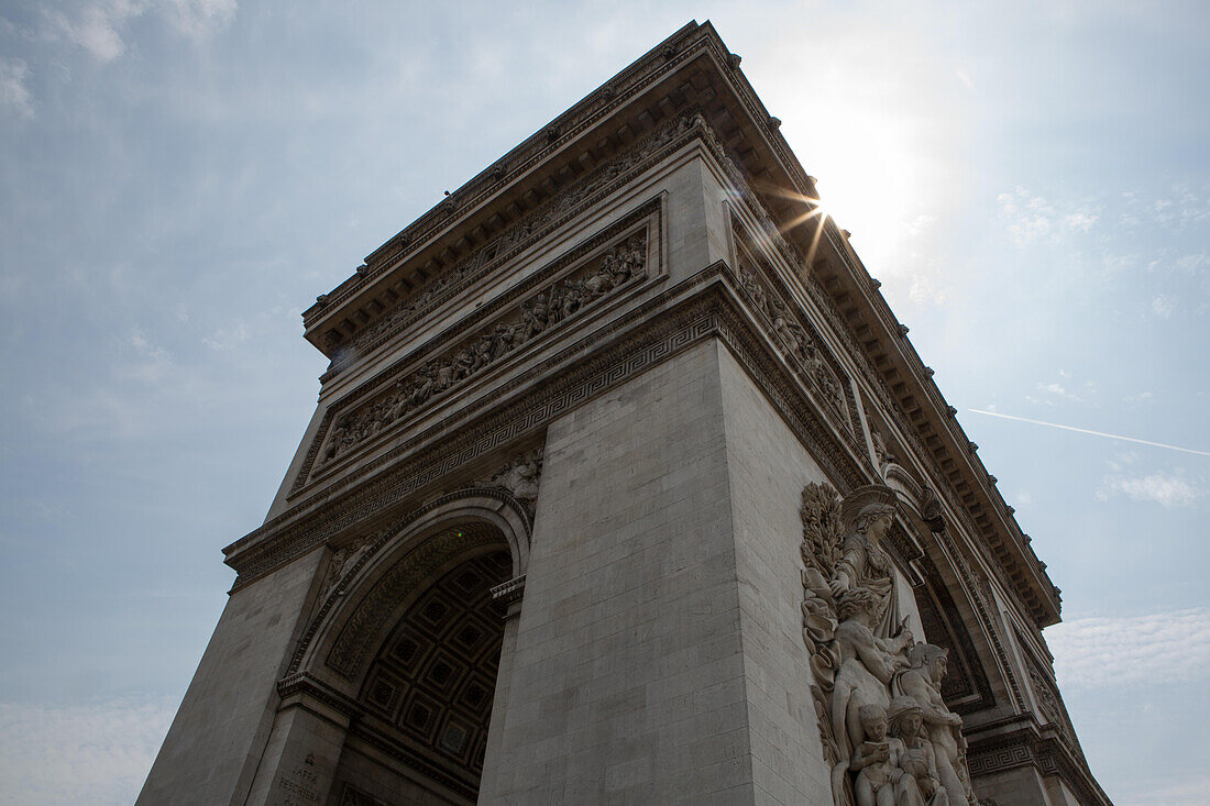 The sun bursts from behind the Arc de Triomphe.,Paris,France