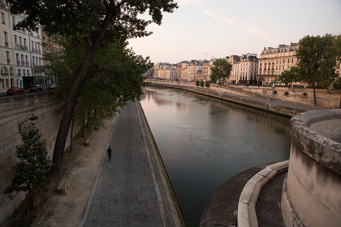 A pedestrian walks along the Seine River near Ile de la Cite.,Paris,France