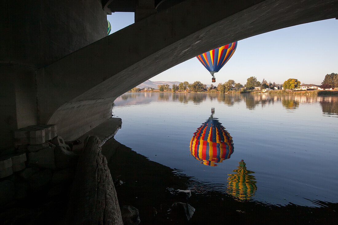 Von unterhalb einer Brücke aus gesehen schwebt ein Heißluftballon der Prosser Balloon Rally über dem Yakima River,Yakima River,Prosser,Washington