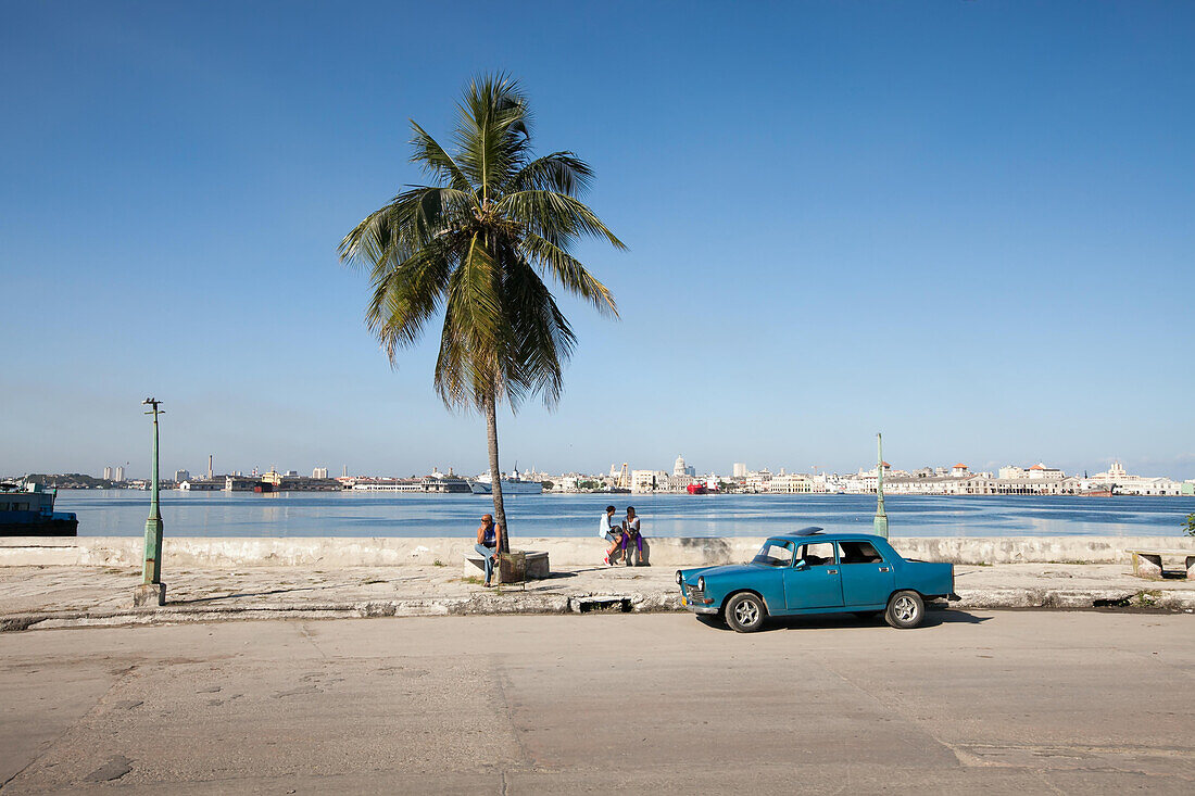 Menschen sitzen auf der Mauer des Malecon, einer Uferpromenade in der Innenstadt von Havanna.,Havanna,Kuba