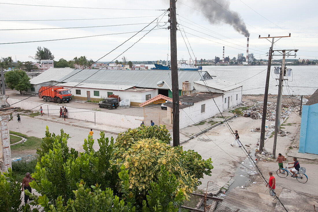 In der Nähe eines Hafen- und Industriegebiets in Cienfuegos laufen Menschen durch die Straßen und Müll bedeckt eine Straße,Cienfuegos,Kuba