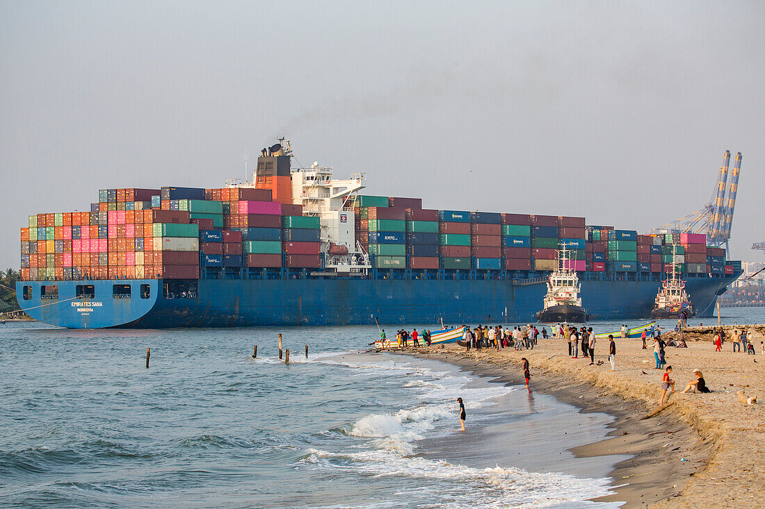 Menschen beobachten ein ankommendes Containerschiff in der Hafenmündung von Kochi, Kerala, Indien, Kochi, Kerala, Indien