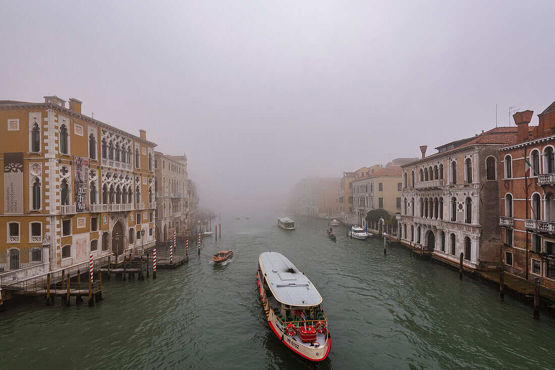 Nebel über dem Canal Grande, während sich ein Wasserbus seinen Weg durch die Wasserstraße bahnt, Venedig, Italien