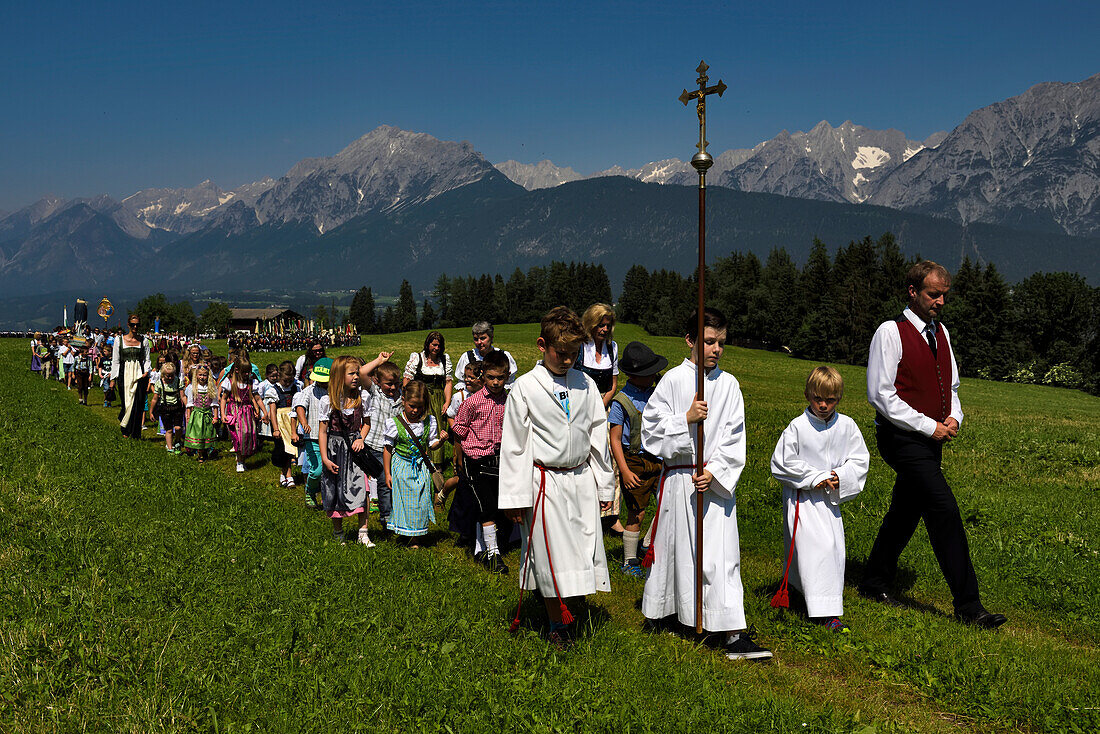 Der Festzug zum Herz-Jesu-Fest betritt eine große Wiese im Karwendelgebirge, Österreich.