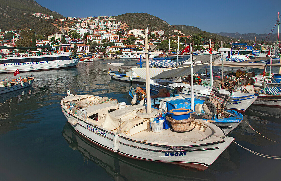 Belebter Hafen mit vertäuten Booten und Häusern am Hang des Mittelmeers bei Kas, Türkei, Kas, Provinz Antalya, Türkei