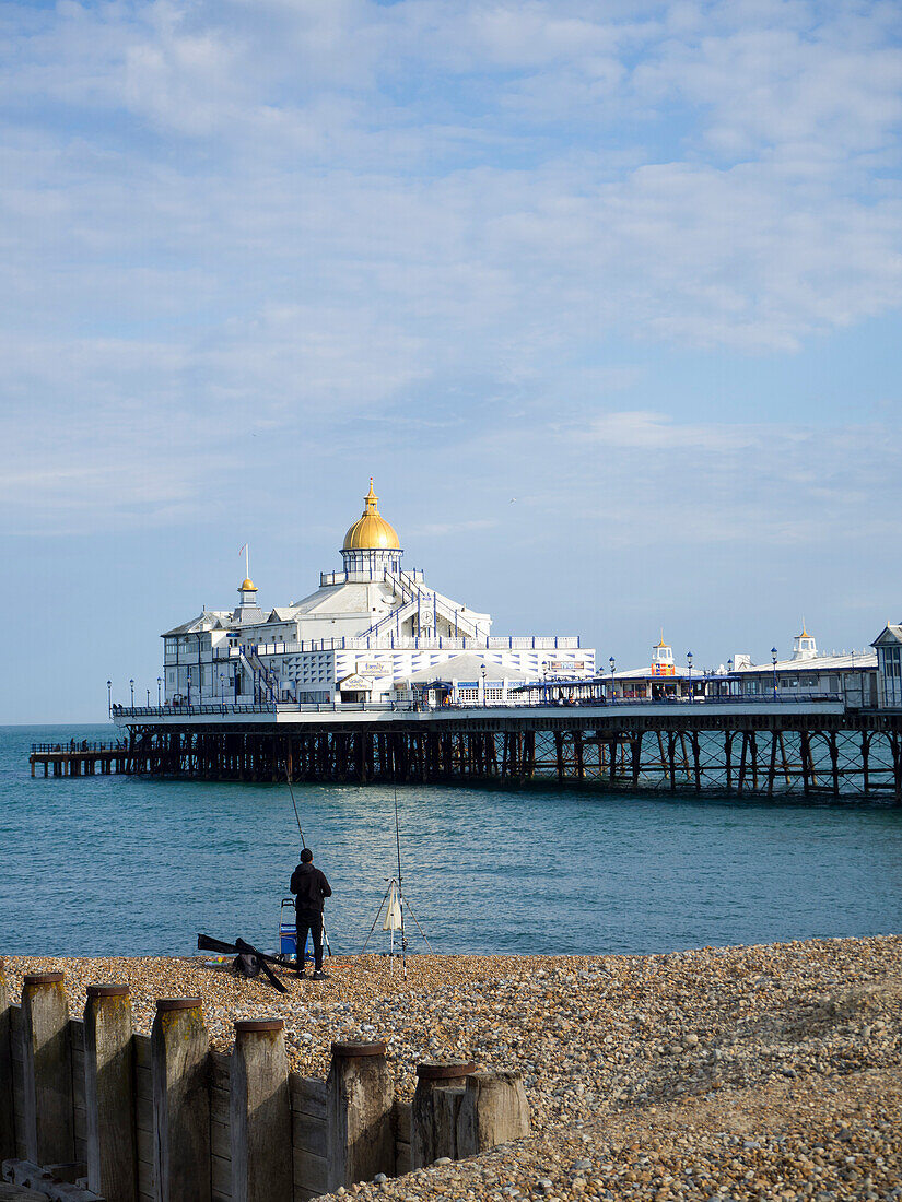 Blick auf den Pier mit goldener Kuppel, ruhige See, blauer Himmel und Kieselstrand,Eastbourne,East Sussex,England