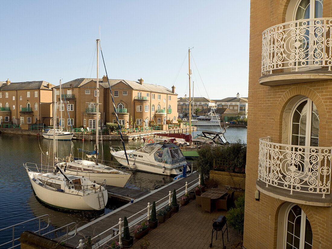 Moored sailing boats in Brighton Marina with view of brick dwellings on a sunny day,Brighton,East Sussex,England