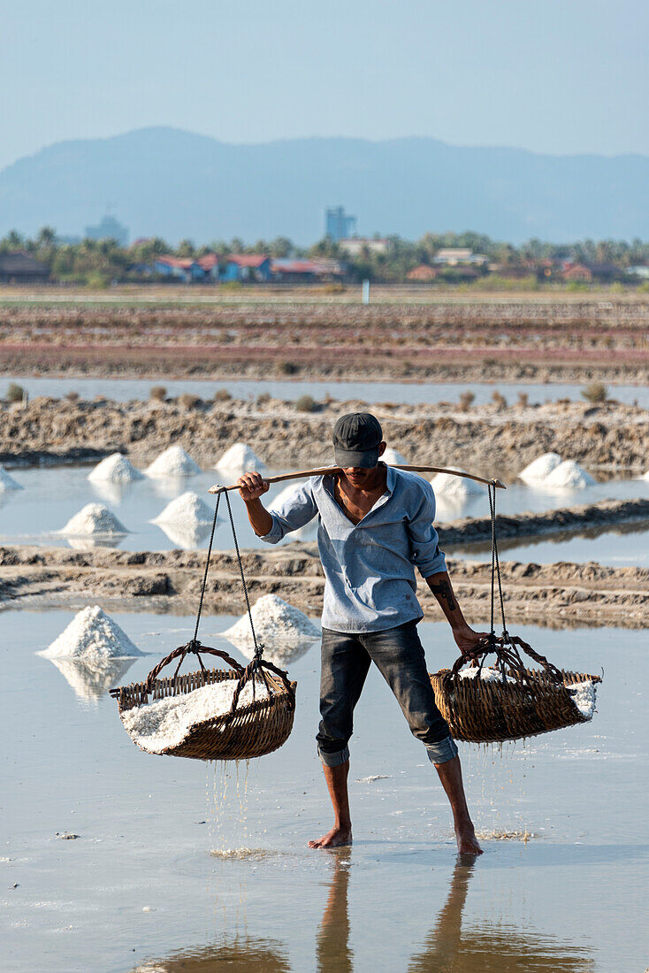 A man carries baskets of rice in a farming community in Southern Cambodia,Kampot,Cambodia