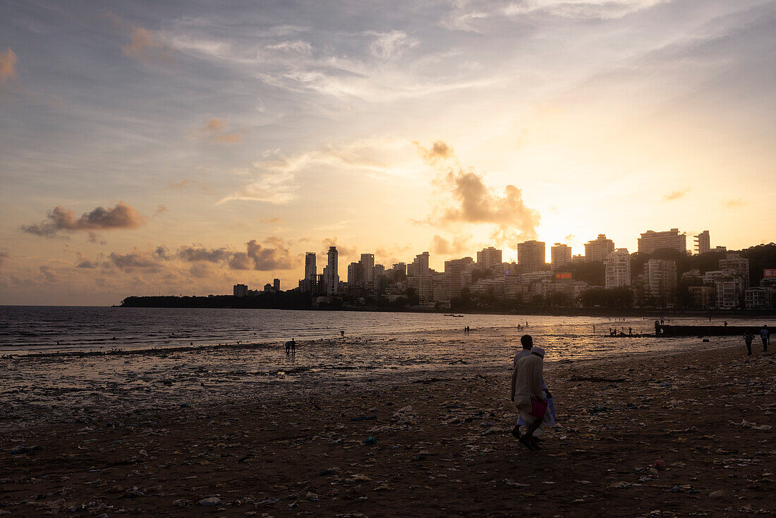 Menschen am Chowpatty Beach bei Sonnenuntergang mit Blick auf die Skyline in Mumbai, Mumbai, Maharashtra, Indien