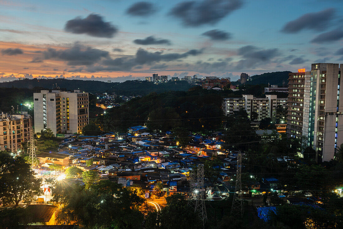 Blick auf einen von Hochhäusern umgebenen Slum bei Sonnenuntergang, Mumbai, Maharashtra, Indien