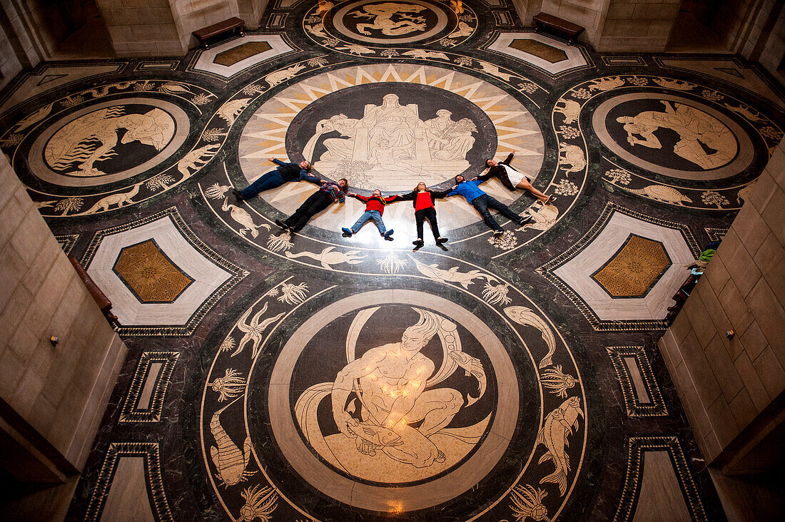 Reisegruppe liegt in einer Reihe auf dem dekorativen Rotunda-Boden im Nebraska State Capitol und blickt nach oben, um die Decke zu bewundern, Lincoln, Nebraska, Vereinigte Staaten von Amerika