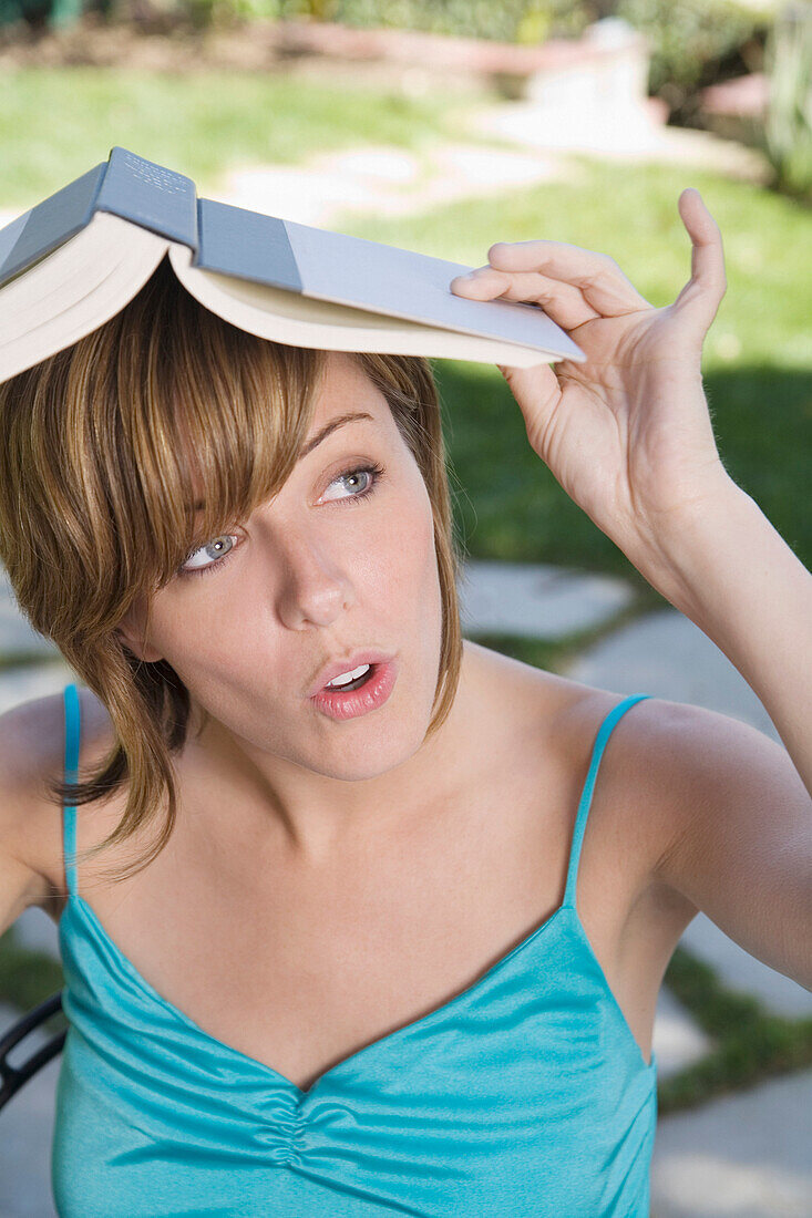 Frau bedeckt Kopf mit Buch