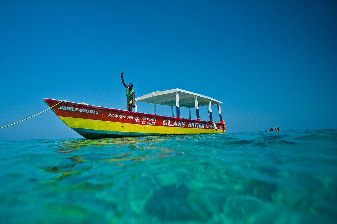 Tour guide waves from his glass bottomed tour boat in the Caribbean,Negril Beach,Jamaica,West Indies